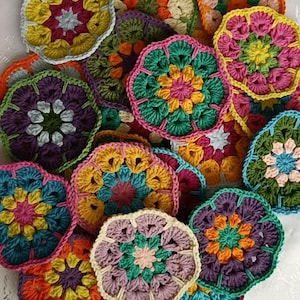 Può includere: Una collezione di motivi floreali all'uncinetto fatti a mano e colorati in varie dimensioni e tonalità. I fiori presentano motivi intricati con sfumature di rosa, giallo, verde, arancione e viola. Questi pezzi decorativi all'uncinetto sono ideali per progetti di artigianato.