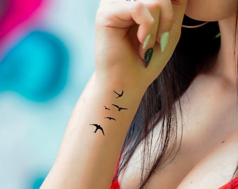 May include: A close-up of a person's wrist with a small tattoo of five black birds flying in a line.
