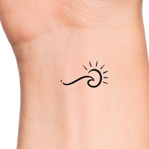 May include: A simple black line drawing tattoo design of a sun and a wave on a person's wrist.