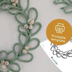 May include: A printable template for a wreath made of green yarn with white beads. The template shows a wreath with a series of loops and beads. The text "Printable template" is on a yellow circle.