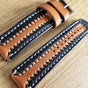 May include: A brown leather watch strap with black and white stitching. The strap has a woven pattern and is designed for a watch with a 20mm lug width.