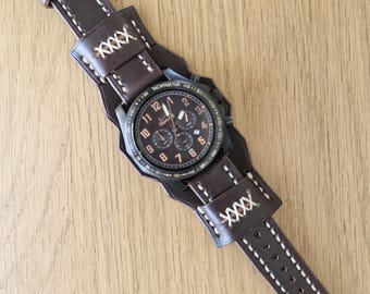 May include: A brown leather watch strap with white stitching and a black chronograph watch with orange accents. The watch face has the text "Tachymeter" and numbers 1-12.
