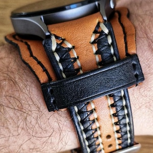 May include: A brown leather watch strap with white stitching and a black leather strap. The strap has a buckle fastening.
