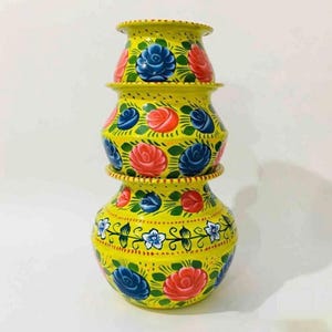 May include: Three yellow ceramic pots stacked on top of each other, each hand-painted with blue and red floral patterns and green leaves. The pots are a decorative item, with a traditional design.