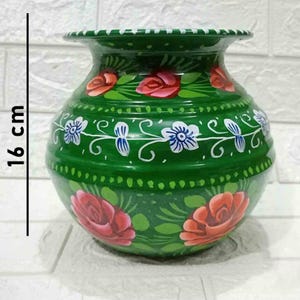 May include: A green ceramic pot with hand-painted floral designs. The pot is 16 cm tall and features red, white, and green flowers.