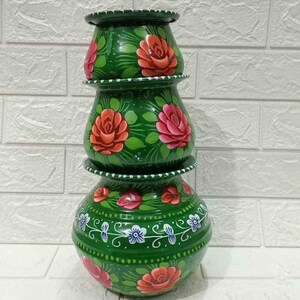 May include: Three-tiered, hand-painted green ceramic pots. Each pot features a floral design with red and pink roses, green leaves, and white and blue accents. The pots are stacked on top of each other.