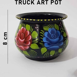 May include: Black truck art pot with hand-painted red and blue roses and green leaves. The pot is 8 cm tall.