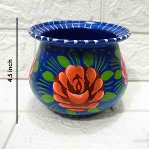 May include: A blue hand-painted ceramic pot with a floral design. The pot is 4.5 inches tall and features red, pink, and green flowers.