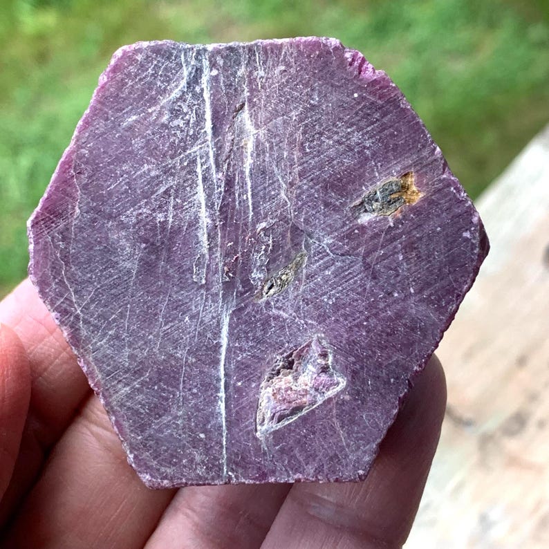 Flat hexagonal face of raw ruby crystal, six-sided outline with fine vertical striations, large hexagonal ruby.