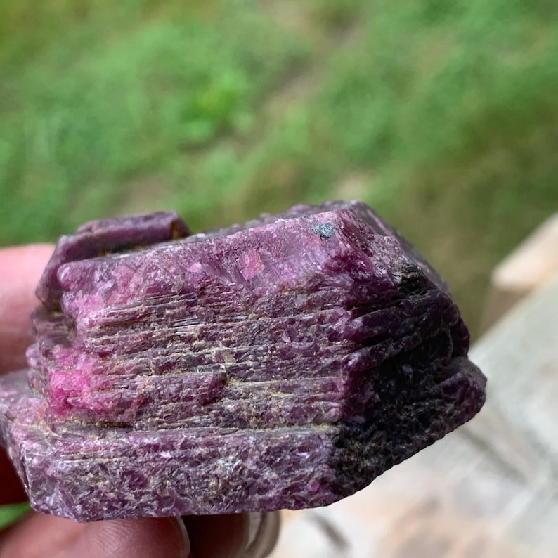 Profile raw ruby crystal, pronounced stacked layers and lighter reflective spots, large rough ruby stone.