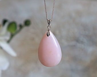 May include: A teardrop-shaped pink opal pendant necklace with a silver chain.