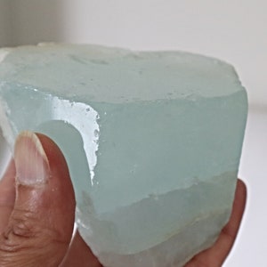 May include: A large, light blue, translucent, natural aquamarine crystal with a rough, irregular shape.