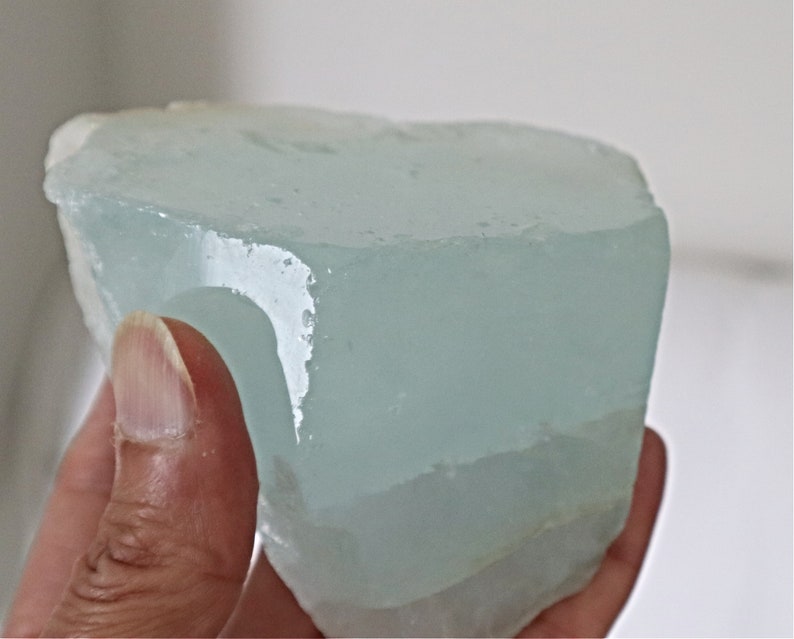 May include: A large, light blue, translucent, natural aquamarine crystal with a rough, irregular shape.