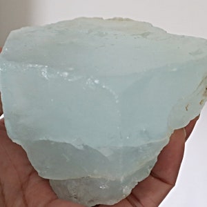 May include: A large, translucent, light blue aquamarine crystal with a rough, natural surface.