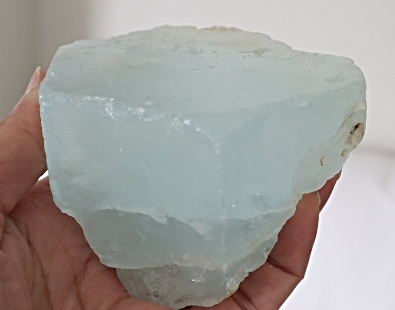 May include: A large, translucent, light blue aquamarine crystal with a rough, natural surface.