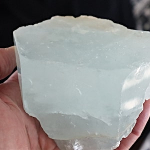 May include: A large, translucent, light blue aquamarine crystal with a rough, natural texture.