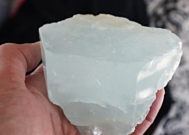 May include: A large, translucent, light blue aquamarine crystal with a rough, natural texture.