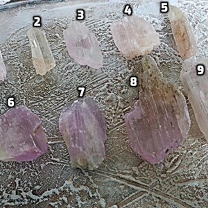 May include: Nine pink and clear crystal specimens of varying sizes and shapes. The crystals are numbered 1 through 9.