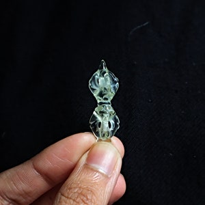 May include: A small, translucent, green, carved, double-sided pendant with a floral design.