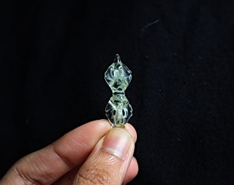 May include: A small, translucent, green, carved, double-sided pendant with a floral design.