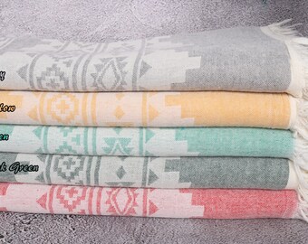 May include: Five Turkish towels stacked on top of each other. The towels are in the colors gray, yellow, green, dark green, and red. Each towel has a geometric pattern.