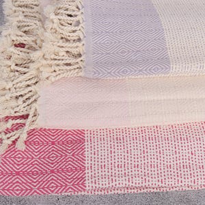 Puede incluir: Toallas de algod&oacute;n plegadas con patrones geom&eacute;tricos en blanco, rosa y lavanda. Las toallas tienen un tejido texturizado y flecos decorativos. Ideales para el ba&ntilde;o o la playa.