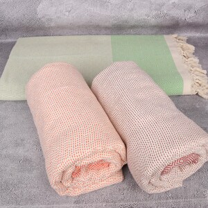 May include: Two rolled up towels, one is a light green and white striped towel, the other is a peach and white striped towel.