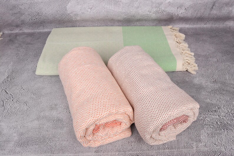 May include: Two rolled up towels, one is a light green and white striped towel, the other is a peach and white striped towel.
