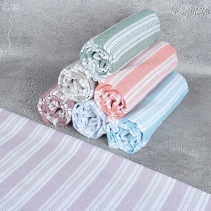 May include: A stack of six rolled towels in various colors, including green, pink, blue, and gray. The towels have a striped pattern and are arranged in a pyramid shape.