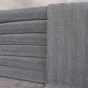 May include: A stack of six rolled, gray and white herringbone-patterned towels with white fringe on the ends. The towels are made of a soft, woven material, and are neatly arranged. The towels are suitable for use in a bathroom or spa.