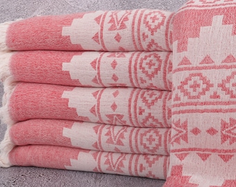 Puede incluir: Una pila de toallas estampadas en rojo y blanco. Las toallas tienen un diseño geométrico en blanco sobre un fondo rojo. Los bordes de las toallas tienen un ribete con flecos.