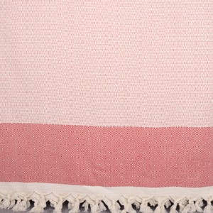 May include: A white and red Turkish towel with a diamond pattern. The towel has a fringe border.