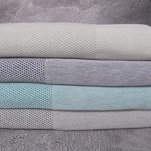 Pode incluir: Quatro toalhas turcas empilhadas umas sobre as outras. As toalhas são nas cores cinza claro, azul marinho, verde pastel e cinza escuro. As toalhas têm uma textura tecida e franjas nas extremidades.