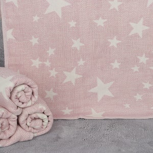 Pode incluir: Três mantas de bebê rosa e branca com padrão de estrelas, enroladas. As mantas são feitas de um tecido macio e texturizado.