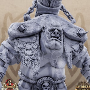 May include: A gray, detailed miniature of a large, muscular, ogre-like creature with a large, toothy mouth. The creature is wearing a chainmail shirt, a leather belt with a skull buckle, and a large, tattered cloak. The miniature is made of plastic and is approximately 3 inches tall.