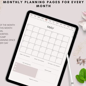Op de afbeelding: Een digitale planner op een tabletscherm met een maandelijkse kalender voor mei. De kalender heeft een eenvoudig zwart-wit ontwerp met een lichtroze achtergrond. De planner bevat ook secties voor het bijhouden van gewoontes, het stellen van doelen en brainstormen.