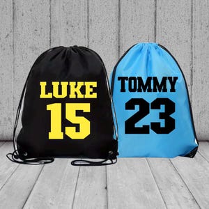 May include: Two drawstring bags, one black with yellow text "LUKE 15" and one blue with black text "TOMMY 23".