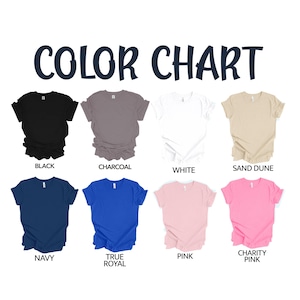 May include: A color chart featuring eight short-sleeve t-shirts arranged in two rows. The colors include black, charcoal, white, sand dune, navy, true royal, pink, and charity pink. The text COLOR CHART is displayed at the top of the image.