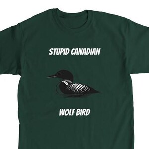 May include: Dark green t-shirt with the text "STUPID CANADIAN" above a graphic of a loon and the text "WOLF BIRD" below. The loon is black and white.