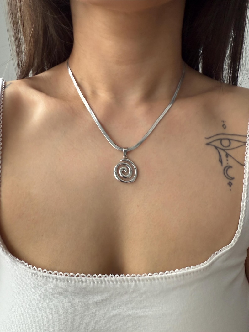 A high-polish silver stainless steel swirl pendant centered on a smooth snake chain, highlighting the hypnotic spiral design for a minimalist goth look.