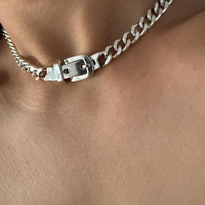 Extreme close-up of the adjustable belt buckle detail on a silver Cuban link chain, showing the high-quality 1-micron silver plating