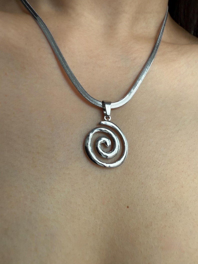 Close-up detail of the 3cm by 2cm swirl pendant, showcasing the durable surgical-grade stainless steel texture and liquid-like movement of the chain.