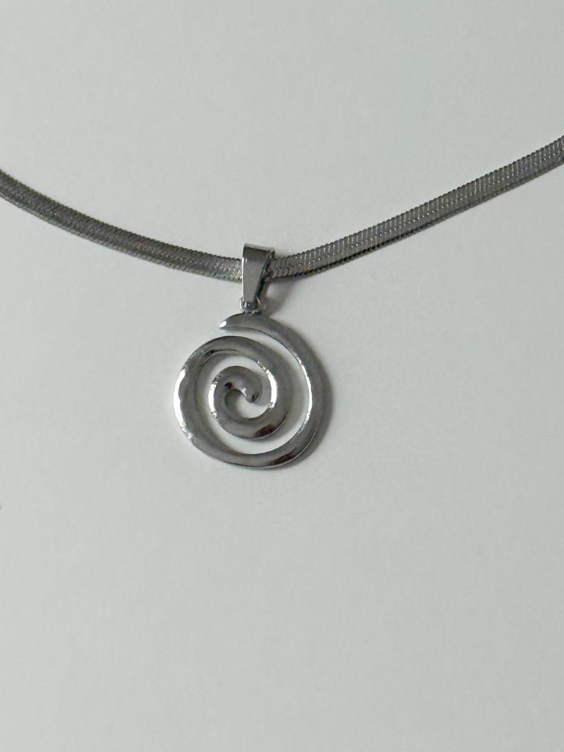 A clear, professional product shot of the stainless steel snake chain and hypnotic swirl pendant, emphasizing its tarnish-proof and waterproof properties.