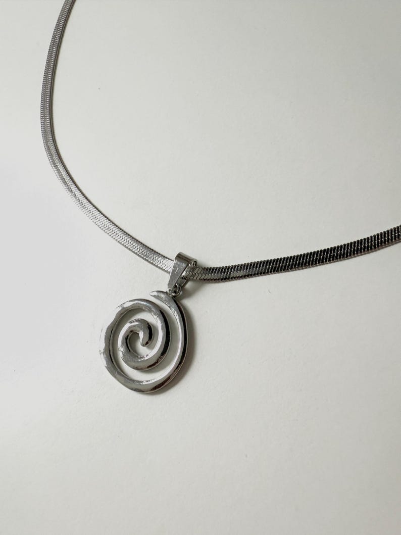 A clear, professional product shot of the stainless steel snake chain and hypnotic swirl pendant, emphasizing its tarnish-proof and waterproof properties.