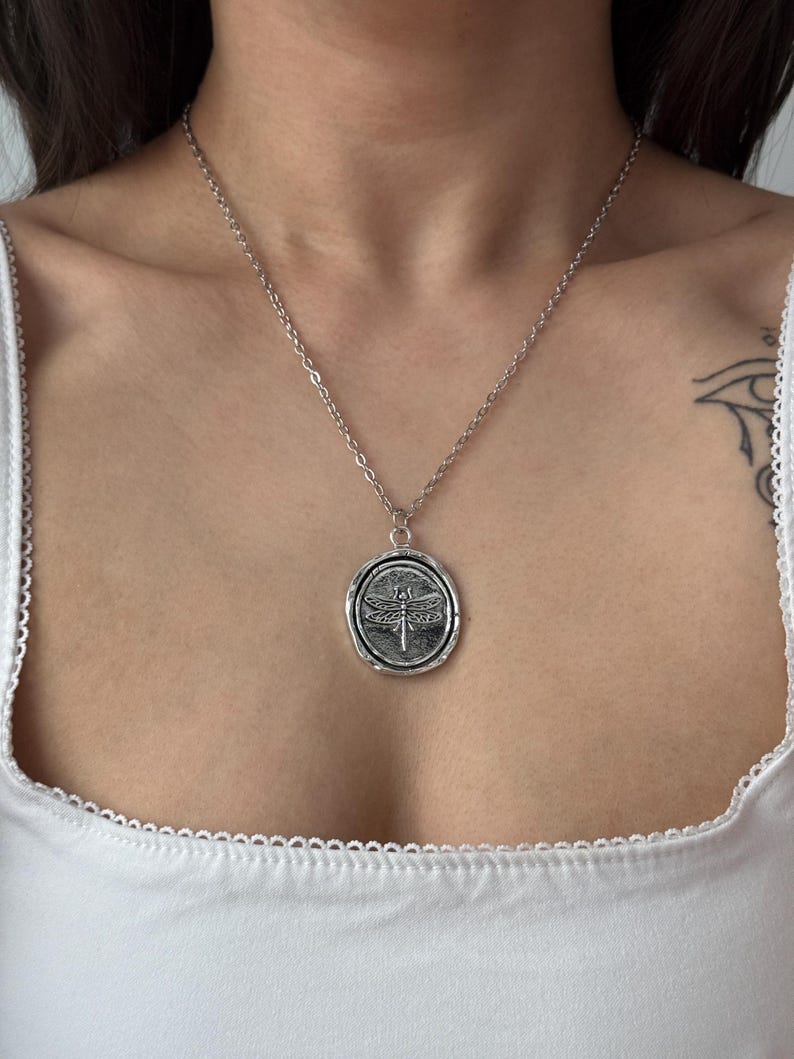 silver tone dragon fly pendnat necklace on girl’s chest