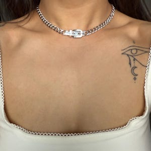 A solid stainless steel buckle necklace layered on a model, emphasizing its versatility with alternative and gothic fashion styles.