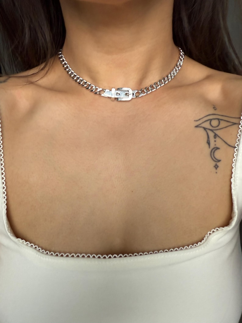 A solid stainless steel buckle necklace layered on a model, emphasizing its versatility with alternative and gothic fashion styles.