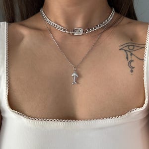 Two silver necklaces layered together, featuring the signature belt buckle Cuban choker as the base statement piece.
