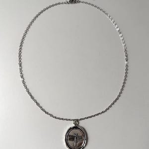 Witchy Amulet Perspective: A side-angle lifestyle image of the dragonfly pendant, highlighting the high-relief metallic texture and silver-toned luster.