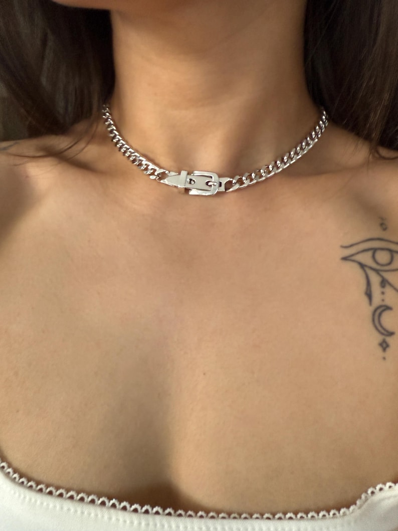 Detailed shot of a silver Cuban link choker with a belt buckle closure, highlighting the polished finish and edgy streetwear style.